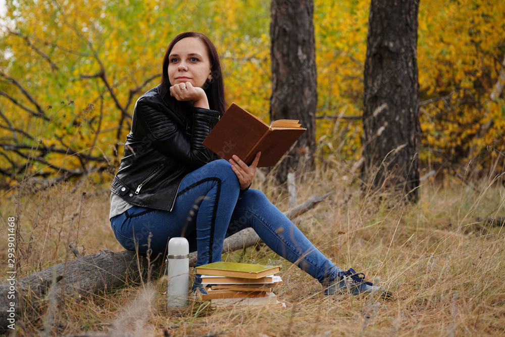 Beautiful woman reading a book in the autumn forest. A woman sits near a tree in an autumn forest and holds a book. Girl reading a book. Autumn season concept and reading Beautiful woman reading a book in the autumn forest. A woman sits near a tree in an autumn forest and holds a book. Girl reading a book. Autumn season concept and reading