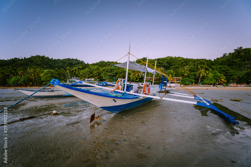 The Philippines's Banca boat. Traditional fishing boat on beach during low tide in evening light. El Nido,Palawan