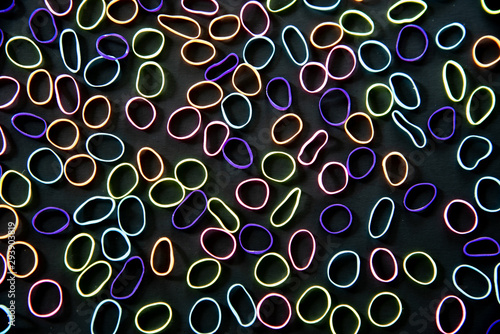 Brightly colored elastic bands forming an abstract pattern on a black background
