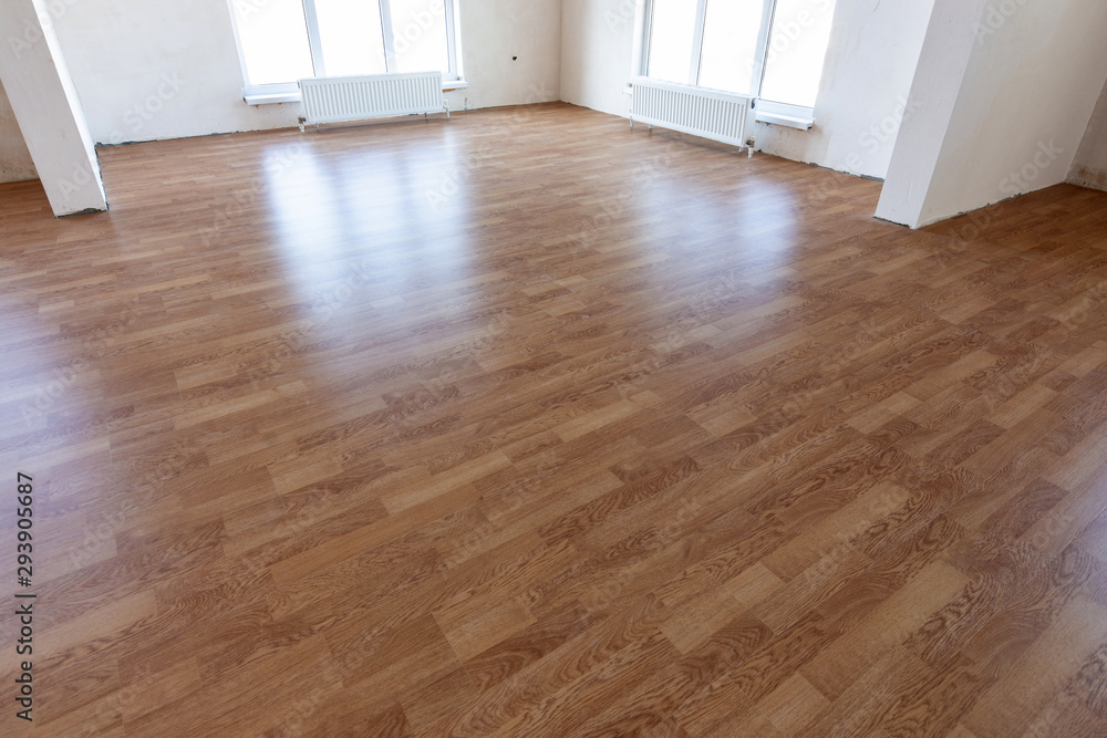 Laminate flooring in the interior of a spacious room in a new building - obrazy, fototapety, plakaty 
