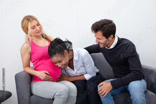 African Friend Listening To Pregnant Friend's Tummy © Andrey Popov