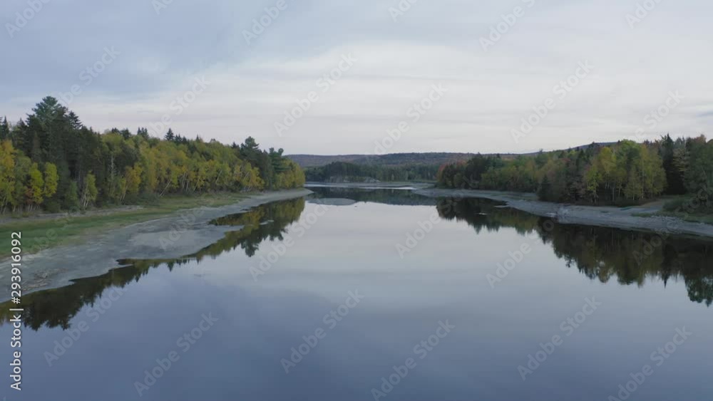 Flying over flat calm reflective idyllic lake water Lush forestry on each side Flying over flat calm reflective idyllic lake water Lush forestry on each side