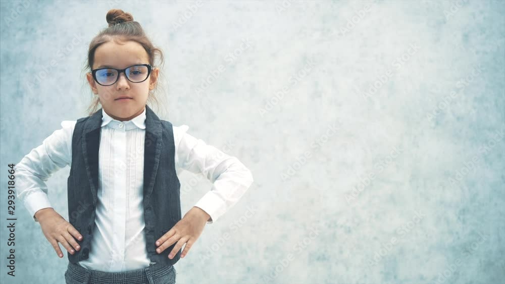 A pretty small business lady stands on a gray background. During this, it removes the glasses and makes a sad look. Serious A pretty small business lady stands on a gray background. During this, it removes the glasses and makes a sad look. Serious