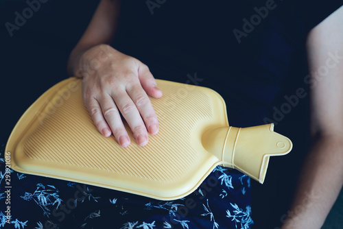 Caucasian woman lying in bed with hot water bag. Close up of woman belly with hot water bottle in bed. Beautiful young woman in bed, with hot water bag on her tummy