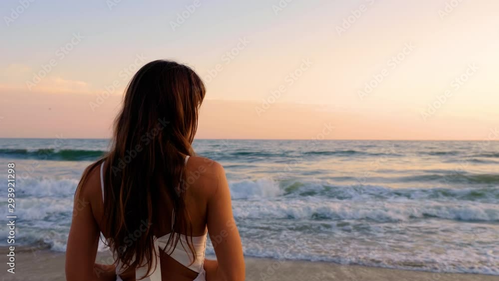 Beautiful woman in a white dress at the beach at sunset