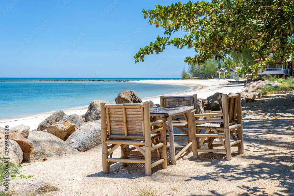 Bamboo table and chairs on tropical sand beach near blue sea water on island Koh Phangan, Thailand