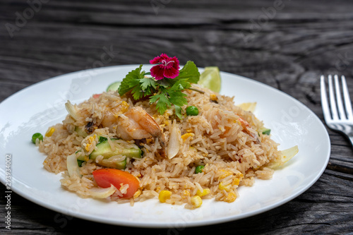 Fried rice with shrimps and vegetables in a white dish on an old wooden table, close up . Thai food , Thai cuisine