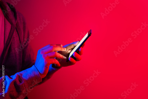 Male hand with smartphone. Finger typing on screen. Neon light photo