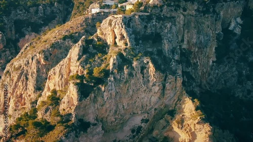 Aerial view of Yellow coast rocks with trees and birds flying around. Luxurious,expensive houses on top of Huge rock cliff near ocean
