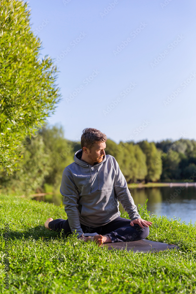 Obraz premium Inspired man doing yoga asanas in city park. Fitness outdoors and life balance concept.