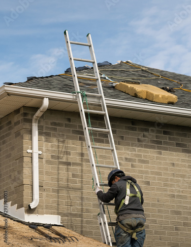 Workman ( roofer ) climibing on a lalder and going uponto the roof