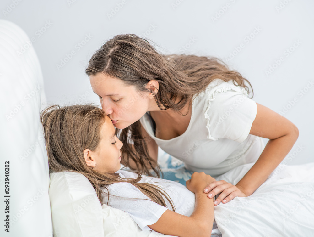 Mother kisses her little daughter before bedtime Mother kisses her little daughter before bedtime