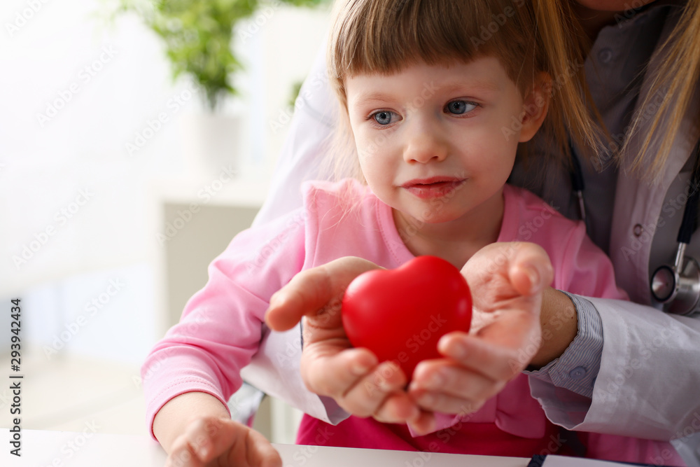 Female doctor and happy little child hold in arms red toy heart closeup. Cardio therapeutist student education CPR 911 life save physician make cardiac physical pulse rate measure arrhythmia lifestyle Female doctor and happy little child hold in arms red toy heart closeup. Cardio therapeutist student education CPR 911 life save physician make cardiac physical pulse rate measure arrhythmia lifestyle