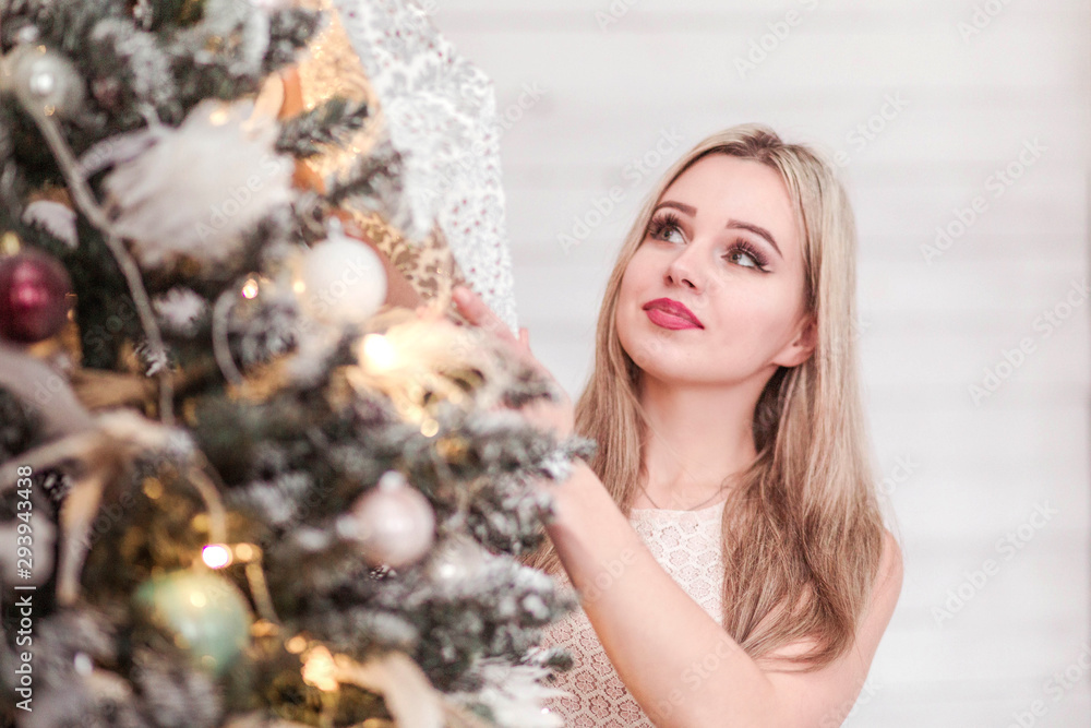 Girl in a pink dress decorates a Christmas tree