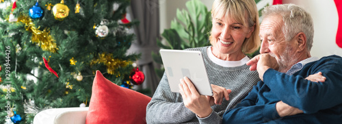 Christmas online shopping. Senior caucasian man and woman sitting on couch using tablet in living room. Very excited. Banner frame.