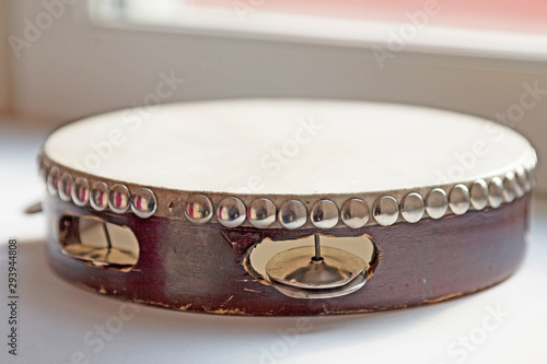 drum with silver colored castanets located in the windowsill, tambourine