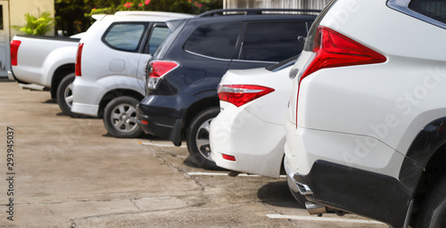 Closeup of rear side of white car with other cars parking in outdoor parking area.