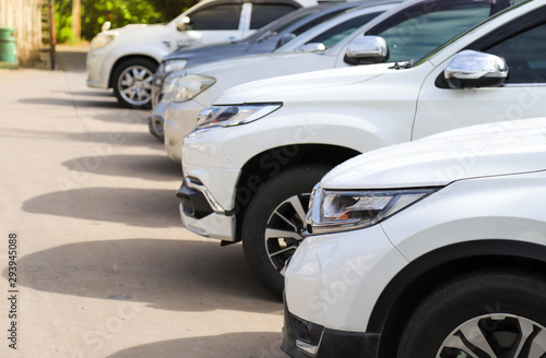 Closeup of front side of white car and other cars parking in outdoor parking area. © Amphon