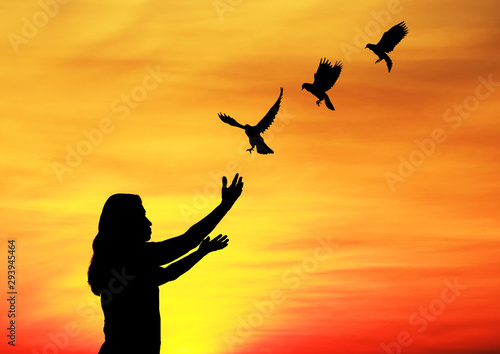 .silhouette of bird flying into lady hand on beautiful sunrise background.freedom concept 