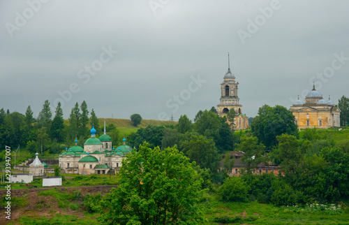 A dilapidated monastery on the river Bank against a dark cloudy sky.