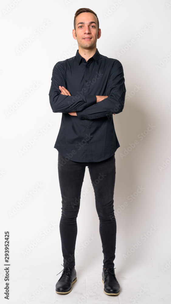 Full body shot of happy young Persian businessman smiling with arms crossed Full body shot of happy young Persian businessman smiling with arms crossed
