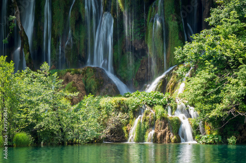 Fototapeta Naklejka Na Ścianę i Meble -  Crystal clear, pure water rushing down mossy rocks into a beautiful azure colored lake at the Plitvice Lakes National Park, Plitvička Jezera, Croatia
