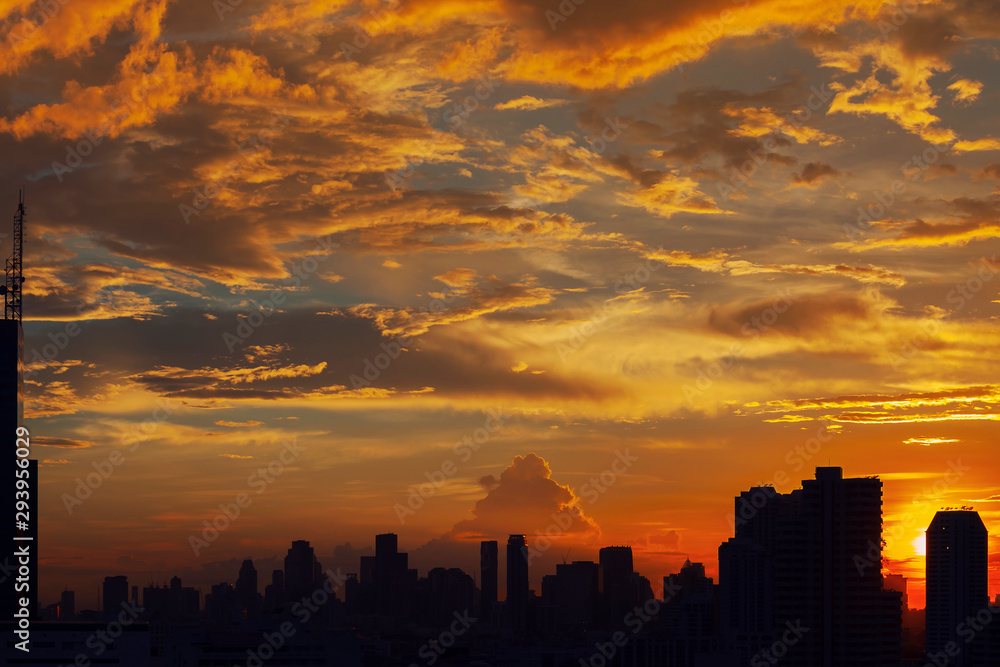 Sunset sky with silhouetted buildings in city. Warm sky in cloudy day. Sunset sky with silhouetted buildings in city. Warm sky in cloudy day.