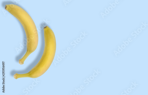 Banana collage. Pattern. Free space. Chilled fruits out of the fridge with condensate droplets. Pastel blue background. Juicy yellow berry. Delicious banan.