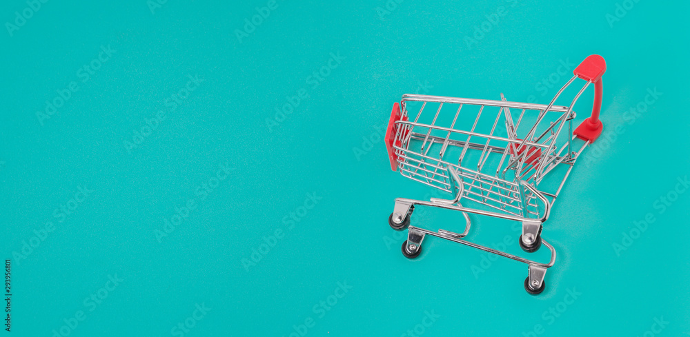 Close up of supermarket grocery push cart for shopping. Shopping trolley on light blue background. Concept of shopping. Copy space for advertisement. 