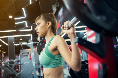 Young sport woman working out with weight lifting in gym. Healthy with fitness and exercise concept.