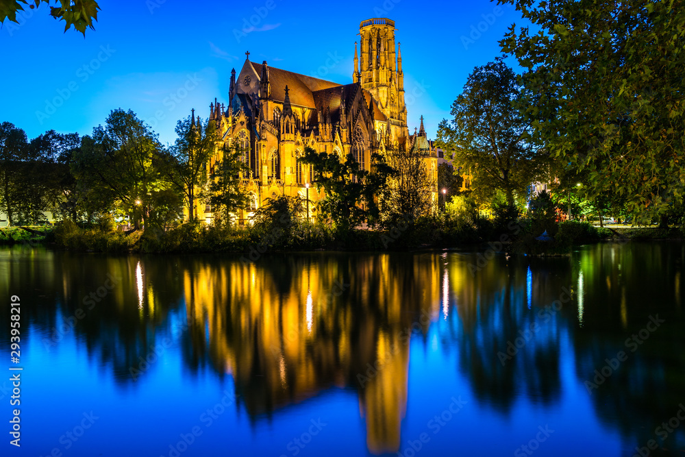 Germany, Church of st john, a gothic church building in downtown stuttgart feuersee, illuminated by night, reflecting in water of lake