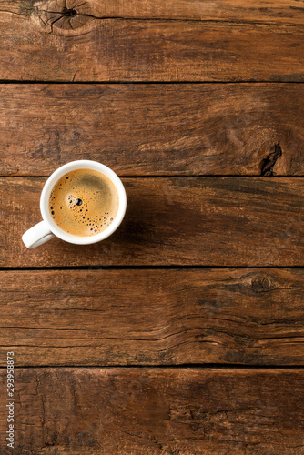 Black coffee cup on retro wooden background with copyspace. Top view