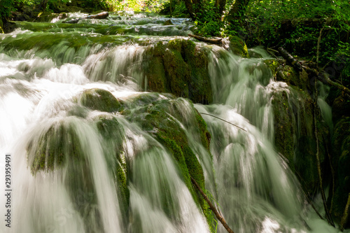 Rushing water cascades down the overgrown natural barriers deep in the dense forest of the Plitvice Lakes National Park, Croatia