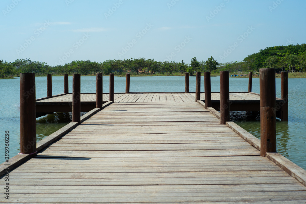Wooden bridge into the lake with trees and horizontal line in background