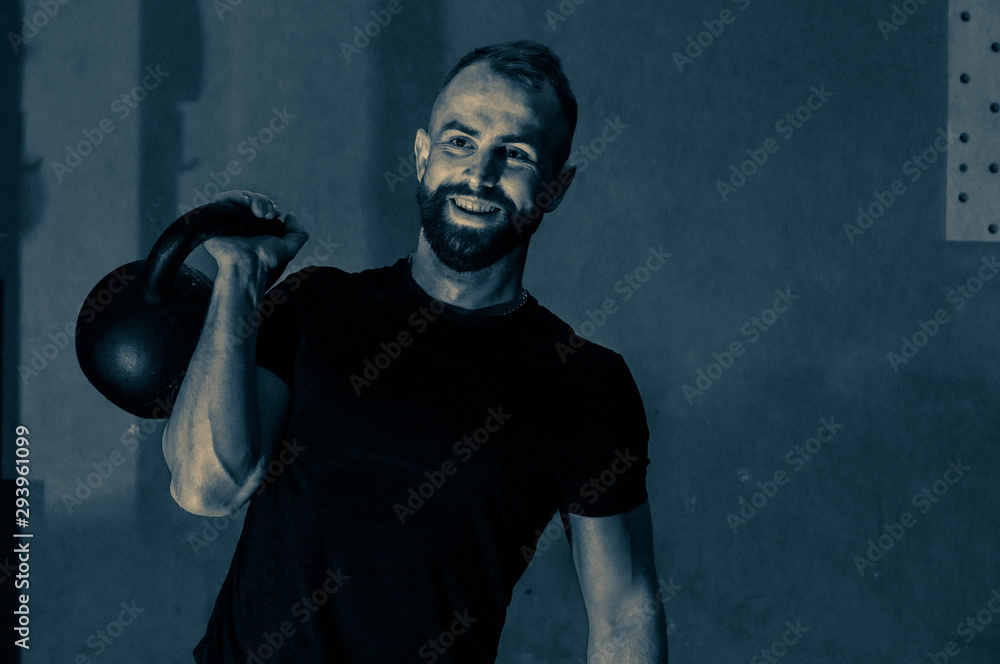 functional training with Kettle Bells Kettlebells, portrait of a young sports guy with a kettlebell in the gym, the concept of a healthy lifestyle and functional training