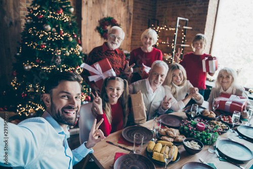 Self-portrait photo of nice cheerful big full family enjoying spending eve noel eating homemade brunch sharing gift tradition showing v-sign in modern industrial loft style interior decorated house
