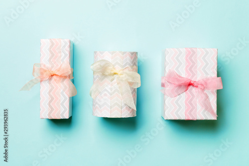 Fototapeta Naklejka Na Ścianę i Meble -  wrapped Christmas or other holiday handmade present in paper with Colored ribbon on blue background. Present box, decoration of gift on colored table, top view