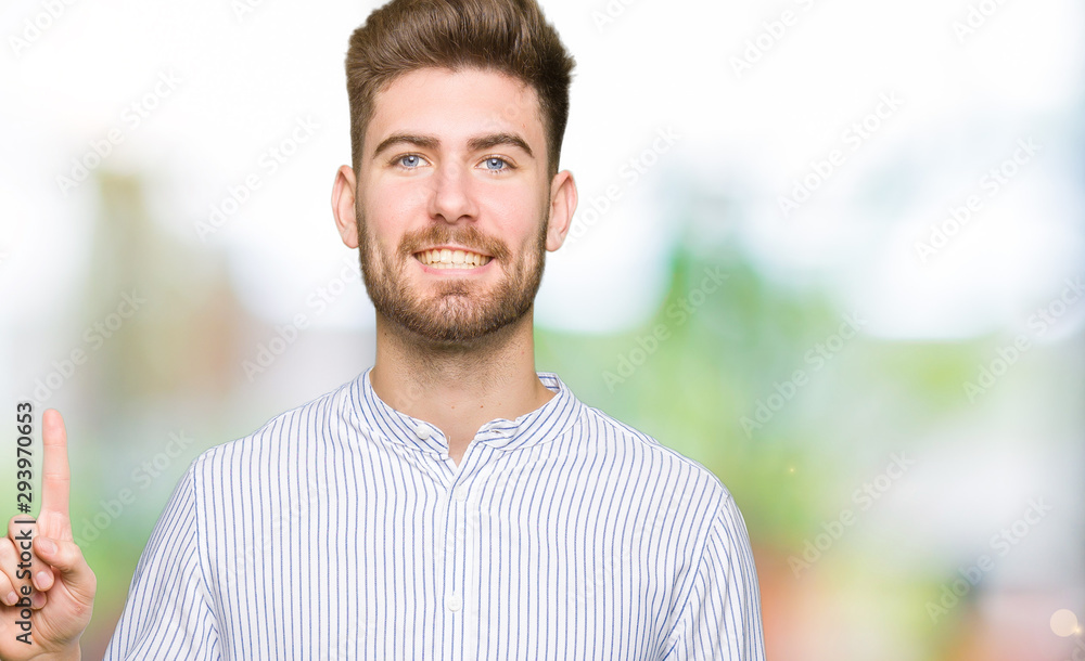Young handsome man showing and pointing up with finger number one while smiling confident and happy. Young handsome man showing and pointing up with finger number one while smiling confident and happy.