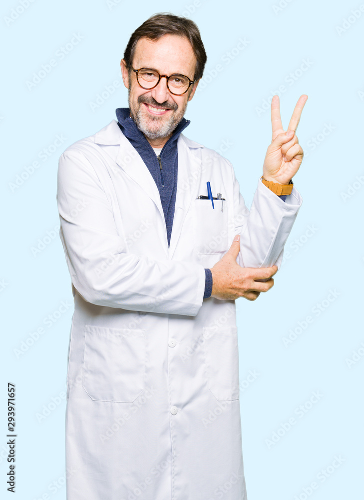 Middle age therapist wearing white coat smiling with happy face winking at the camera doing victory sign. Number two. Middle age therapist wearing white coat smiling with happy face winking at the camera doing victory sign. Number two.