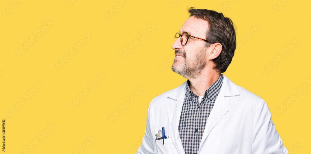 Middle age doctor men wearing medical coat looking away to side with smile on face, natural expression. Laughing confident. Middle age doctor men wearing medical coat looking away to side with smile on face, natural expression. Laughing confident.