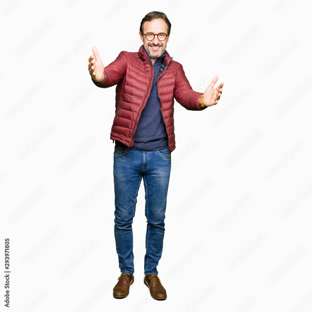 Middle age handsome man wearing glasses and winter coat looking at the camera smiling with open arms for hug. Cheerful expression embracing happiness. Middle age handsome man wearing glasses and winter coat looking at the camera smiling with open arms for hug. Cheerful expression embracing happiness.