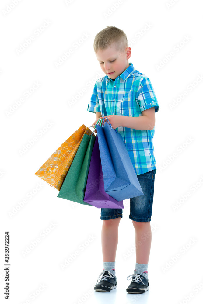 Little boy waving multicolored paper bags. He goes shopping Little boy waving multicolored paper bags. He goes shopping
