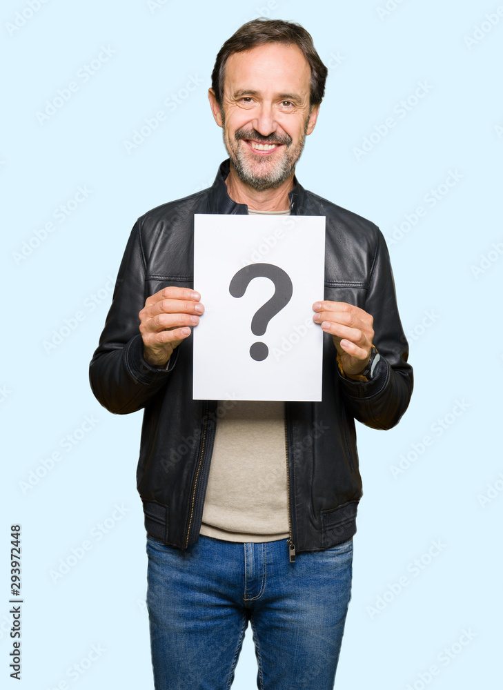Handsome middle age man holding paper with question mark with a happy face standing and smiling with a confident smile showing teeth Handsome middle age man holding paper with question mark with a happy face standing and smiling with a confident smile showing teeth