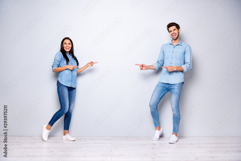 Full length photo of guy and lady advising buy new product for low price indicating fingers empty space wear casual jeans clothes isolated grey color background Full length photo of guy and lady advising buy new product for low price indicating fingers empty space wear casual jeans clothes isolated grey color background