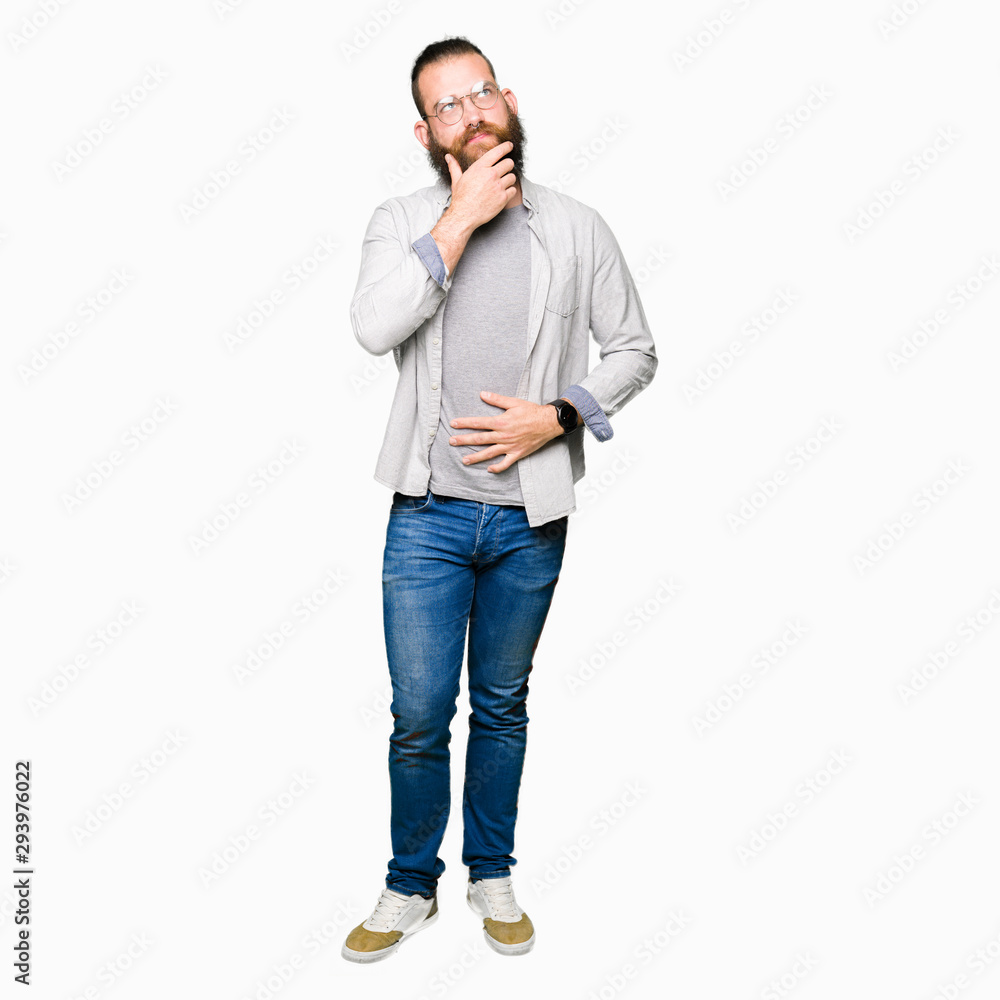 Fototapeta premium Young blond man wearing glasses with hand on chin thinking about question, pensive expression. Smiling with thoughtful face. Doubt concept.