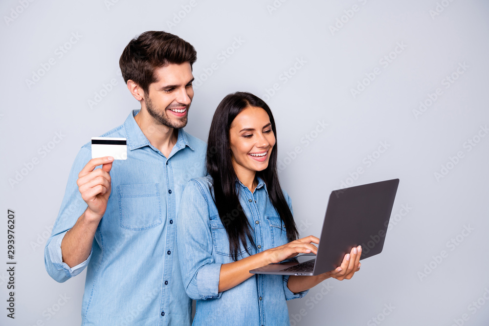 Photo of cheerful trendy charming business couple of two people together working on project holding credit card laptop isolated over grey color background Photo of cheerful trendy charming business couple of two people together working on project holding credit card laptop isolated over grey color background