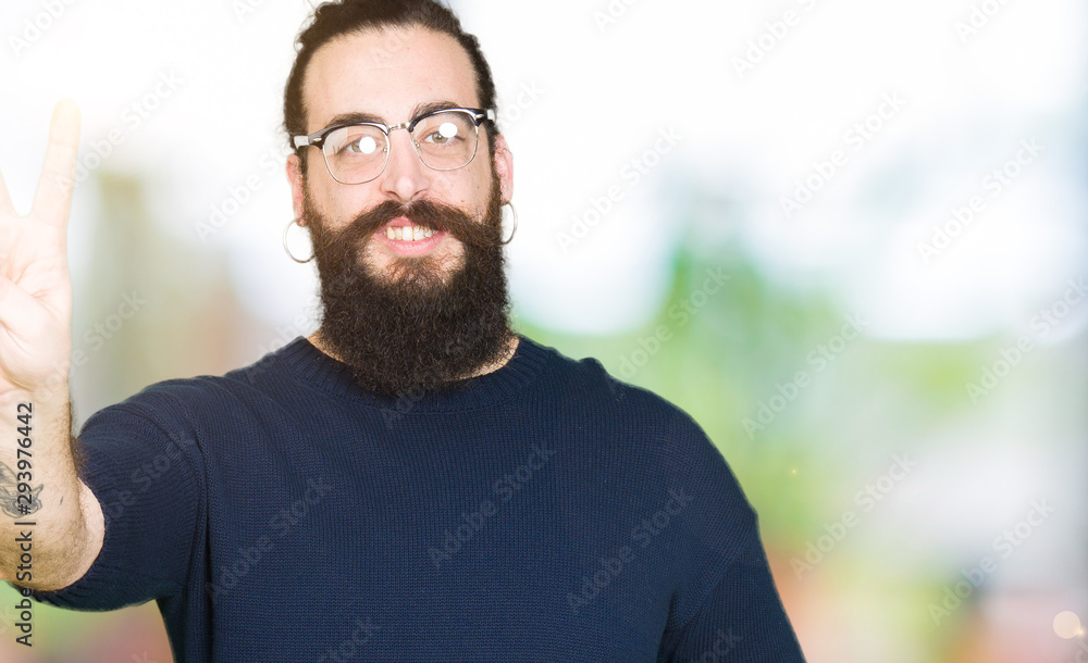 Young hipster man with long hair and beard wearing glasses showing and pointing up with fingers number two while smiling confident and happy. Young hipster man with long hair and beard wearing glasses showing and pointing up with fingers number two while smiling confident and happy.