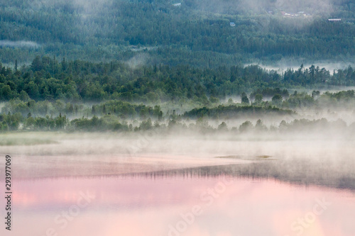 Sunset reflections in a forest lake with fog