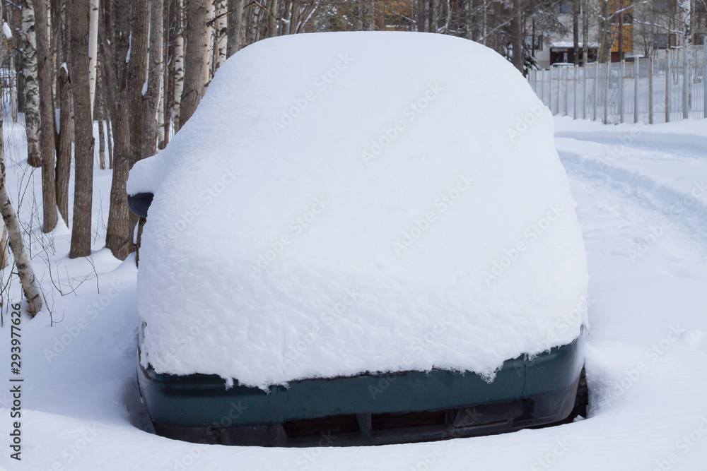 A car under the snow against the background of trees. A car under the snow against the background of trees.