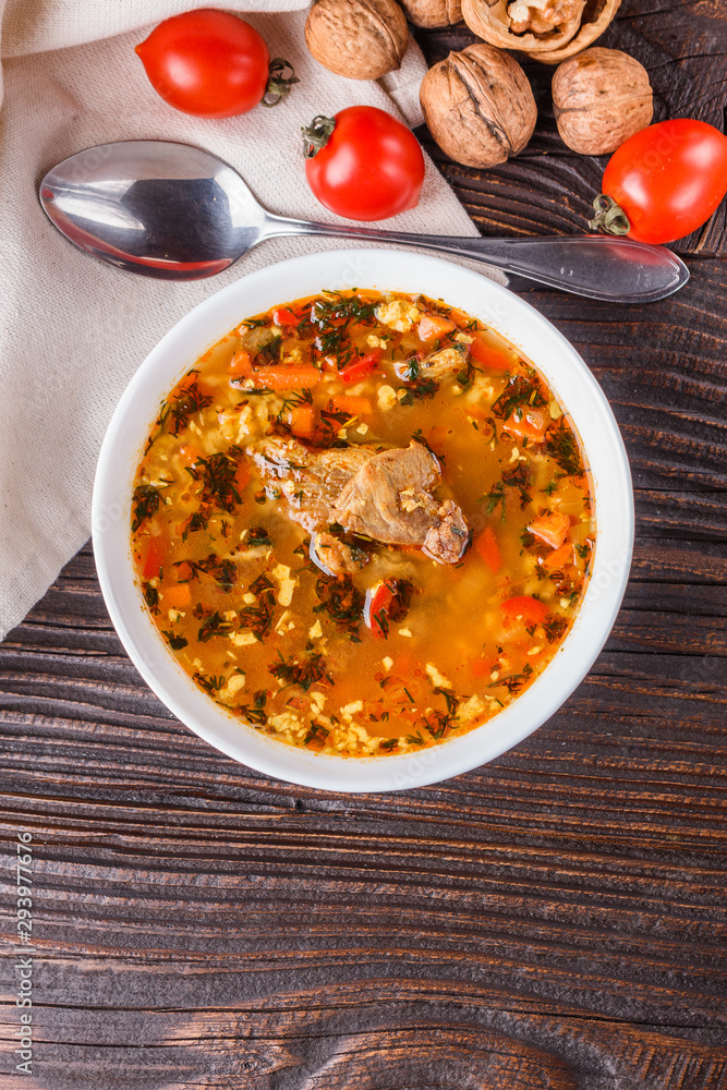 Georgian soup. Kharcho with rice, tomato, beef, garlic and herbs in bowl on wooden table Georgian soup. Kharcho with rice, tomato, beef, garlic and herbs in bowl on wooden table